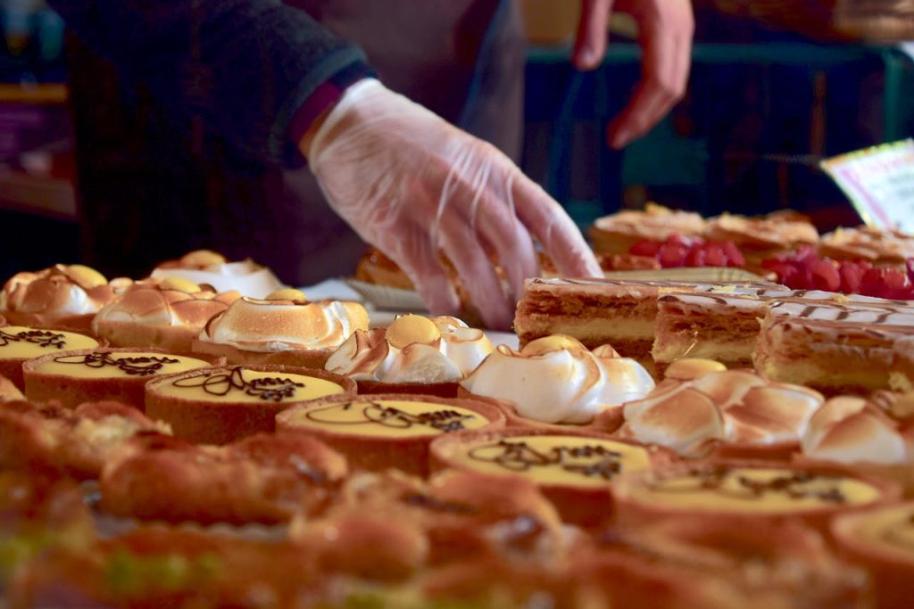 person-holding-a-cupcake-1005406 Delicious assorted pastries including custard slices and meringues at a London market stall.